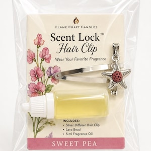 Puede incluir: Una pinza para el cabello plateada con forma de estrella de mar, una cuenta de lava roja porosa y un frasco de 5 ml de aceite aromático sobre una tarjeta Flame Craft Candles Scent Lock Hair Clip, con ilustración de guisantes de olor y texto.
