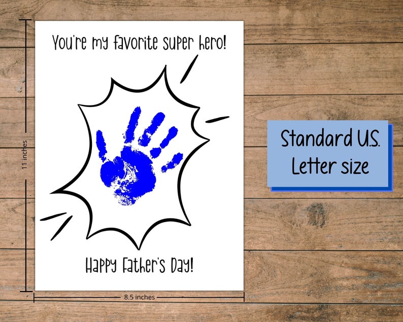 Peut inclure: Une carte blanche avec du texte noir qui dit "You're my favorite super hero!" et "Happy Father's Day!" avec une empreinte de main bleue &agrave; l'int&eacute;rieur d'une bulle de dialogue de style bande dessin&eacute;e noire et blanche. La carte mesure 8,5 pouces par 11 pouces.