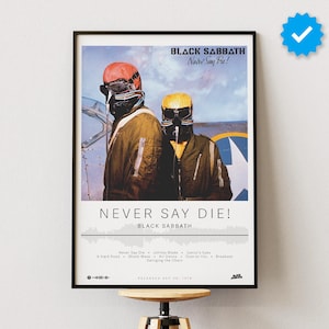 May include: A framed poster of the Black Sabbath album "Never Say Die!" featuring a black and white photo of two men in flight suits, one wearing a red helmet and the other a yellow helmet. The album title is in black text with a white outline. The album's tracklist is listed below the title.