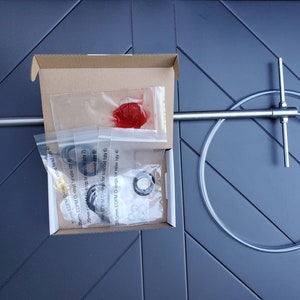 Puede incluir: Un juego de piezas de repuesto para un grifo de cerveza, que incluye una manija de grifo de acero inoxidable, un tubo de plástico transparente, un lubricante rojo y un paquete de juntas tóricas. El paquete incluye el texto "29mm EDPM O-rings for solenoid (qty 6)" y "24.5mm EDPM O-rings for valve (qty 4)".