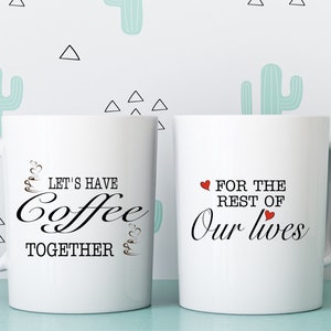 May include: Two white ceramic coffee mugs with black text. One mug reads "LET'S HAVE Coffee TOGETHER" and the other reads "FOR THE REST OF Our lives". The mugs have a handle and are set against a light blue and white cactus pattern.