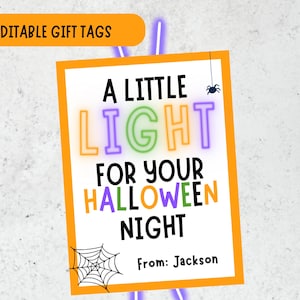 May include: A rectangular Halloween gift tag with an orange border on a white background. The text reads A LITTLE LIGHT FOR YOUR HALLOWEEN NIGHT in colorful letters, with a small spider, a spider web, and the text From: Jackson at the bottom.