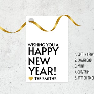 Op de afbeelding: Een wit cadeau-etiket met gouden tekst die "Wishing you a Happy New Year!" en "The Smiths" zegt. Een gouden hartje staat naast de naam. Instructies voor het bewerken, downloaden, afdrukken, knippen en bevestigen van het etiket aan een cadeau staan ​​aan de rechterkant van het etiket.
