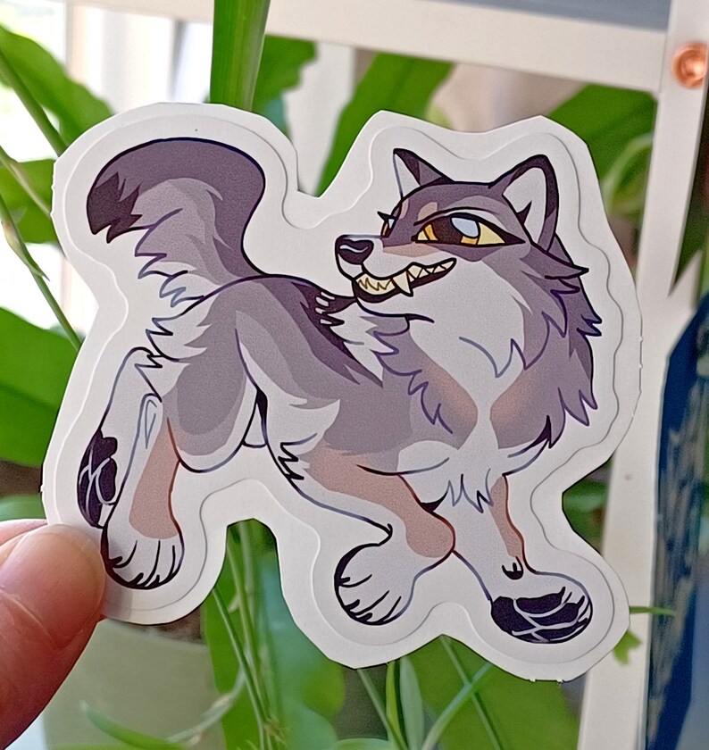 May include: A sticker of a cartoon wolf with a gray and white fur pattern. The wolf is looking to the right with its mouth open, showing its teeth. The wolf has a yellow eye and a blue eye.
