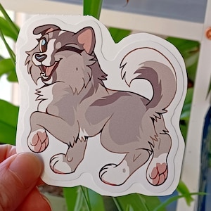 May include: A gray and white cartoon husky dog sticker with a happy expression, winking, and its tongue sticking out. The dog is standing on its hind legs with its front paws raised.