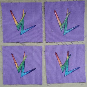 May include: Four square patches of lavender fabric. Each patch features a rainbow-colored, glittery lightning bolt design. The lightning bolt is outlined in black. The patches are arranged in a two-by-two grid.