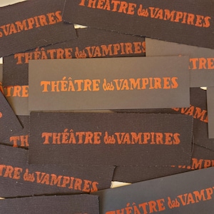 May include: Close-up of several black fabric patches with the text "THEATRE des VAMPIRES" printed in orange.