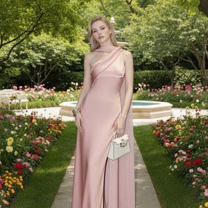 Puede incluir: Un vestido de seda rosa p&aacute;lido de un solo hombro con una abertura alta. El vestido se combina con un peque&ntilde;o bolso blanco y tacones plateados adornados. El fondo presenta un jard&iacute;n con un camino de piedra y una fuente.
