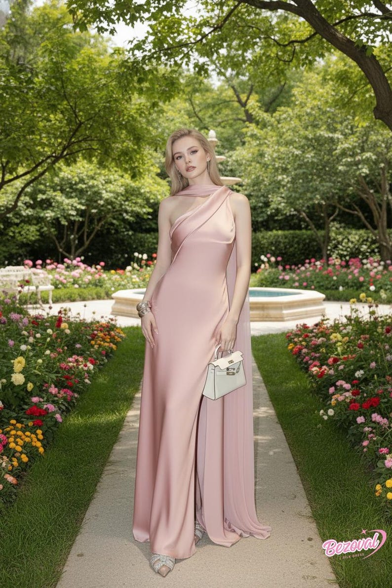 Puede incluir: Un vestido de seda rosa p&aacute;lido de un solo hombro con una abertura alta. El vestido se combina con un peque&ntilde;o bolso blanco y tacones plateados adornados. El fondo presenta un jard&iacute;n con un camino de piedra y una fuente.