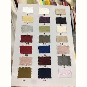 May include: A color swatch card featuring twenty fabric samples in various colors, including white, gold, purple, black, silver, green, red, blue, pink, and gray. The samples are numbered and arranged in rows and columns.