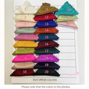 May include: A color chart displaying samples of silk dress fabric in various shades. The samples are arranged in rows and columns, with each color labeled with a number. The chart includes colors such as cream, gold, red, blue, orange, and teal. The text "SILK DRESS COLORS" is visible.