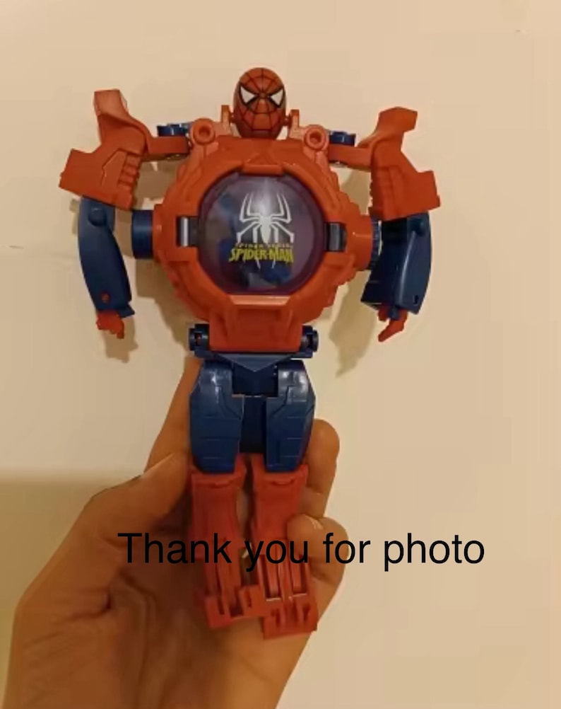 May include: Red and blue plastic toy robot with a Spider-Man face and the words "Amazing Spider-Man" on the chest. The robot has articulated arms and legs.