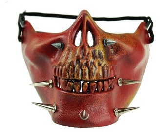 May include: Red skull mask with silver spikes and a black strap. The mask has a detailed skull design with teeth and eye sockets.