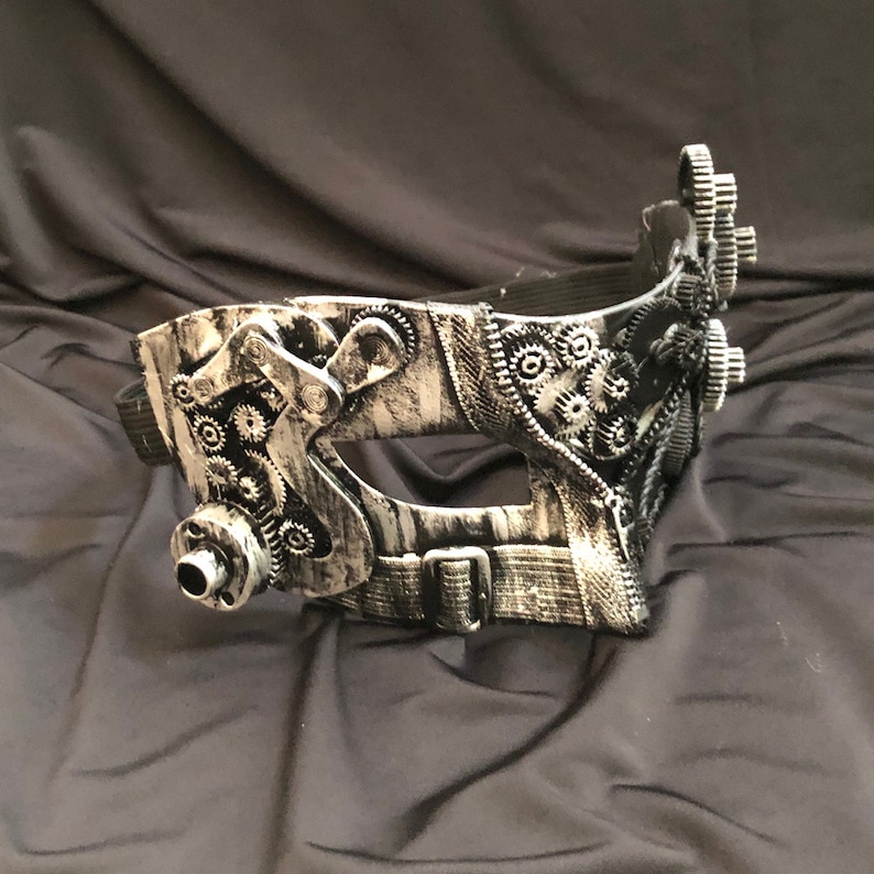 May include: A silver and black steampunk-style masquerade mask with intricate gear details and a black strap.