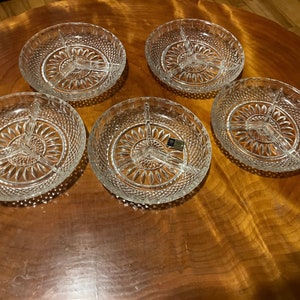 May include: Set of four clear glass divided serving dishes with a diamond pattern. The dishes are arranged on a wooden surface.