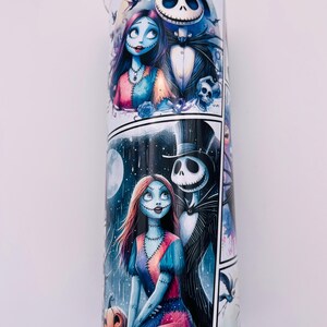 May include: A white tumbler with a colorful cartoon image of Jack Skellington and Sally from the Nightmare Before Christmas. The image is in a comic book style with multiple panels.