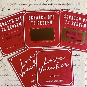 May include: Red scratch-off cards with white text that reads "SCRATCH OFF TO REDEEM" and "Love Voucher". One card says "Date night" and another says "Breakfast in bed". The cards are for Valentine's Day.
