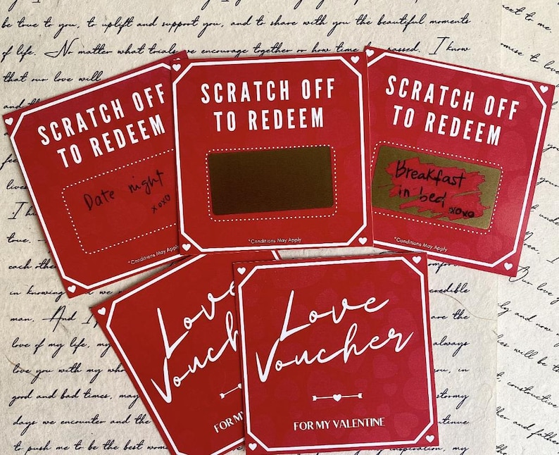 May include: Red scratch-off cards with white text that reads "SCRATCH OFF TO REDEEM" and "Love Voucher". One card says "Date night" and another says "Breakfast in bed". The cards are for Valentine's Day.