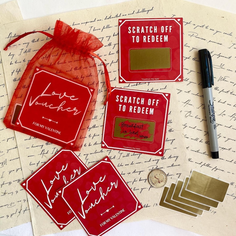 May include: Red love vouchers with white text, some with scratch-off areas. A red mesh bag holds some vouchers. The text reads "Love Voucher" and "Scratch Off To Redeem". A black marker and gold scratch-off stickers are also present.