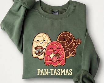 May include: Green sweatshirt with a graphic of three smiling pan dulce characters. One holds a mug, another holds pastries, and the third holds a pan dulce. The text "PAN-TASMAS" is printed below the characters.