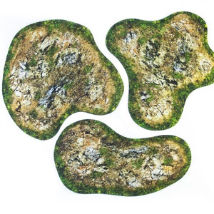 May include: Three irregularly shaped terrain pieces with a detailed, textured surface. The pieces feature a mix of brown, gray, and green colors, resembling a miniature landscape with rocks and vegetation. Ideal for tabletop gaming.