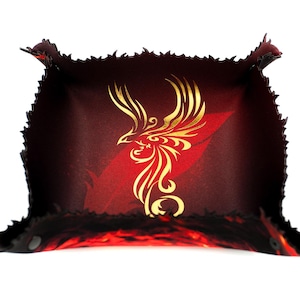 Op de afbeelding: Een vierkante, donkerrode leren tray met een gouden feniksontwerp. De tray heeft een getextureerde, gekartelde rand en een rood-zwart interieur. De feniks is gecentreerd op de basis van de tray.