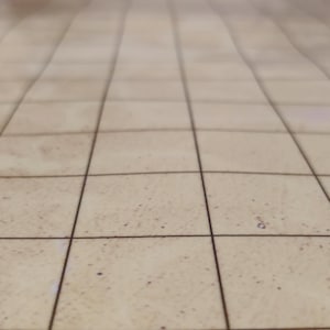 Puede incluir: Superficie beige con patr&oacute;n de cuadr&iacute;cula, posiblemente una mesa o suelo, con l&iacute;neas oscuras que crean un efecto de baldosas. La superficie tiene un aspecto ligeramente texturizado, con sutiles variaciones de color.