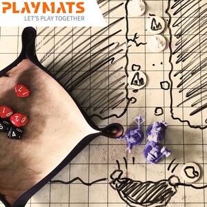 Puede incluir: Una configuraci&oacute;n de juego de rol de mesa con una bandeja de dados, dados, piezas de juego y un mapa dibujado a mano. La bandeja de dados es de color canela con un borde negro. Los dados son rojos y negros. Las piezas del juego son moradas y blancas.