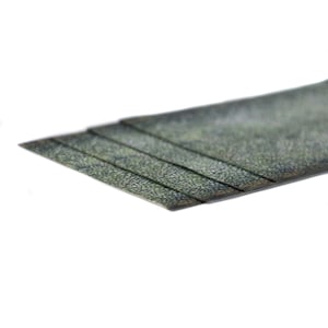 May include: A close-up shot of a stack of textured, dark green material. The material is layered, with each layer slightly offset, creating a stepped effect. The surface has a speckled pattern, and the edges are clean and straight.