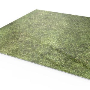 Puede incluir: Tapete de juego rectangular verde y marrón con un patrón hexagonal. El tapete tiene una esquina ligeramente curvada, revelando una parte inferior blanca. La superficie tiene una apariencia texturizada, lo que sugiere un diseño de hierba o terreno.