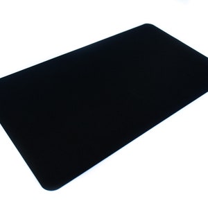 Puede incluir: Una alfombrilla de ratón rectangular negra con esquinas redondeadas. La alfombrilla es de color negro mate sólido y está sobre un fondo blanco. La alfombrilla está diseñada para uso informático.