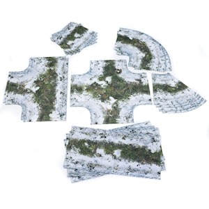 Könnte beinhalten: Eine Sammlung von Geländefliesen mit einem verschneiten, grasbewachsenen Design. Das Set enthält verschiedene Formen, wie z. B. Querschnitte, Kurven und gerade Stücke, ideal für Tabletop-Spiele oder den Modellbau. Die Fliesen weisen ein detailliertes, realistisches Aussehen auf.