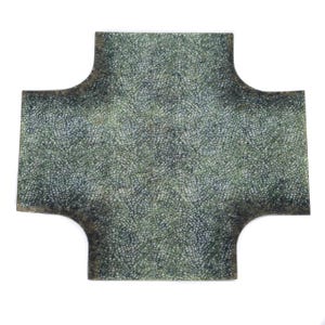 May include: A cross-shaped tile with a mosaic design in green and grey hues. The edges have a darker, aged look. The tile is set against a white background.