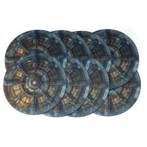 Puede incluir: Juego de siete posavasos redondos con un diseño detallado y envejecido similar a la piedra. Los posavasos presentan un patrón circular con tonos azules, marrones y dorados, que se asemeja a un elemento arquitectónico antiguo.
