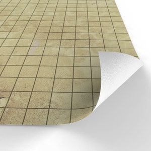 Puede incluir: Una superficie de baldosas beige con l&iacute;neas de cuadr&iacute;cula oscuras, parcialmente enrollada para revelar una parte inferior blanca. Las baldosas tienen un aspecto texturizado, creando una apariencia realista y envejecida. El dise&ntilde;o general sugiere un revestimiento de suelo o de mesa.