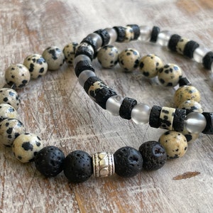 May include: Two bracelets made with black lava rock beads, clear glass beads, and speckled brown and black beads.