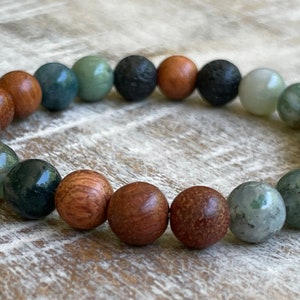 May include: A bracelet made of green, brown, and black beads. The beads are round and have a smooth finish. The bracelet is made of natural materials and is perfect for everyday wear.