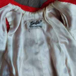 May include: A red velvet doll coat with a white satin lining. The coat has a label that reads "Barbie&reg; &copy; by Mattel".
