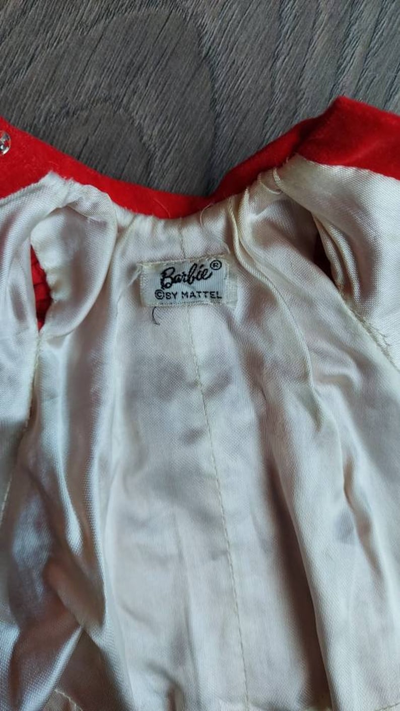 May include: A red velvet doll coat with a white satin lining. The coat has a label that reads "Barbie&reg; &copy; by Mattel".