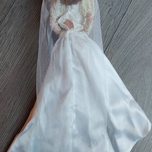May include: A white bridal gown with a long veil. The gown is made of a satin-like fabric and has a fitted bodice and a flowing skirt.