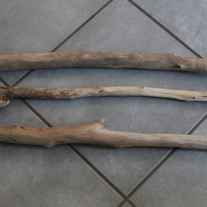 May include: Three pieces of driftwood of varying sizes and shapes. The driftwood is light brown in colour and has a natural, weathered look.