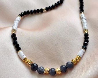 Puede incluir: Collar de cuentas negras, blancas y grises con detalles dorados. El diseño presenta una mezcla de cuentas redondas y cilíndricas, creando un accesorio elegante y sofisticado.