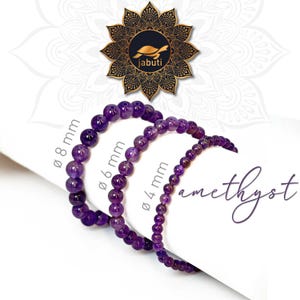 Könnte beinhalten: Drei violette Amethyst-Perlenarmbänder in einer Reihe angeordnet. Die Armbänder haben Perlen mit Durchmessern von 8 mm, 6 mm und 4 mm. Der Text "jabuti" erscheint mit einem Schildkrötenlogo und das Wort "amethyst" ist in Schreibschrift.