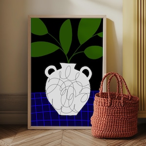 Puede incluir: Una impresión artística enmarcada que presenta un jarrón blanco con hojas verdes sobre un fondo negro. El jarrón tiene un diseño garabateado. Un patrón de cuadrícula azul está en la parte inferior. Una bolsa tote roja tejida está frente a la impresión.