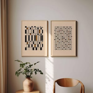May include: Two framed abstract art prints. One features a vertical arrangement of black, gold, and white rectangles. The other has a grid-like pattern of black and gold rectangles. Both are in light wood frames, displayed on a neutral wall.