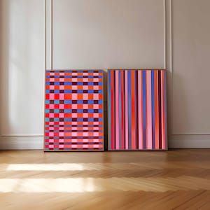 Può includere: Due opere d'arte astratte incorniciate. Una presenta una griglia di quadrati colorati nelle tonalità di rosso, rosa, blu e viola. L'altra ha strisce verticali in colori simili. Entrambe sono esposte contro un muro neutro e un pavimento in parquet.