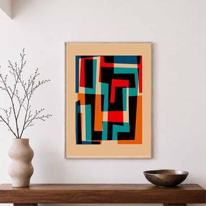 May include: A framed rectangular wall art print featuring an abstract composition of overlapping geometric shapes in black, red, orange, and teal against a solid beige background. The artwork is displayed in a thin, light-colored wooden frame.