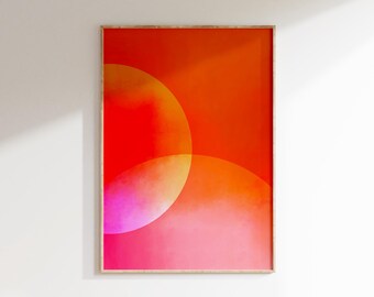 May include: Abstract art print featuring overlapping circles in shades of red, orange, and pink. The artwork is framed in a natural wood frame and hangs on a white wall. The color palette creates a warm and vibrant aesthetic.