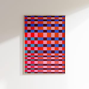 May include: A framed artwork featuring a vibrant, geometric pattern of colorful squares. The design incorporates shades of red, pink, orange, blue, and brown, creating a visually striking composition. The artwork is displayed on a white wall.