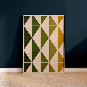 May include: A framed print featuring a geometric pattern of pink, green and yellow triangles. The print is in a wooden frame and is hanging on a dark blue wall.